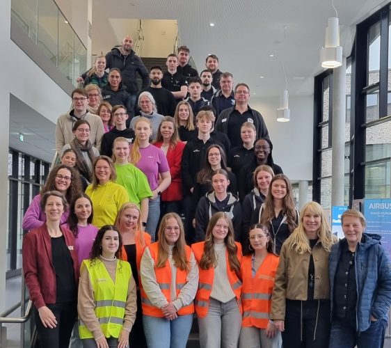 Circa 40 überwiegend weiblich gelesene Menschen stehen zum Gruppenfoto auf einer Treppe. Einige tragen Warnwesten.